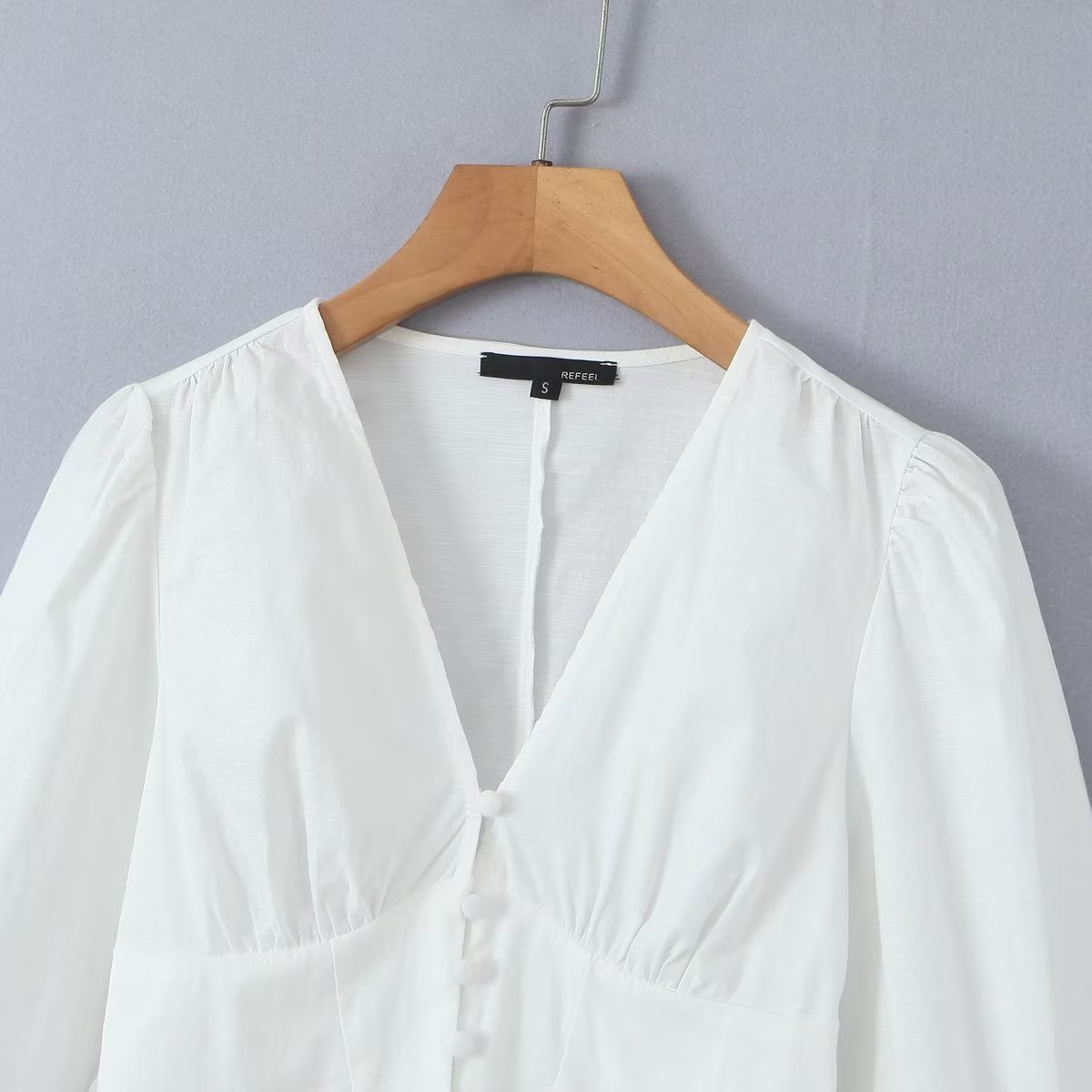 Camisa blanca asimétrica irregular con escote en V y mangas abullonadas de estilo vintage francés, corte entallado y cintura